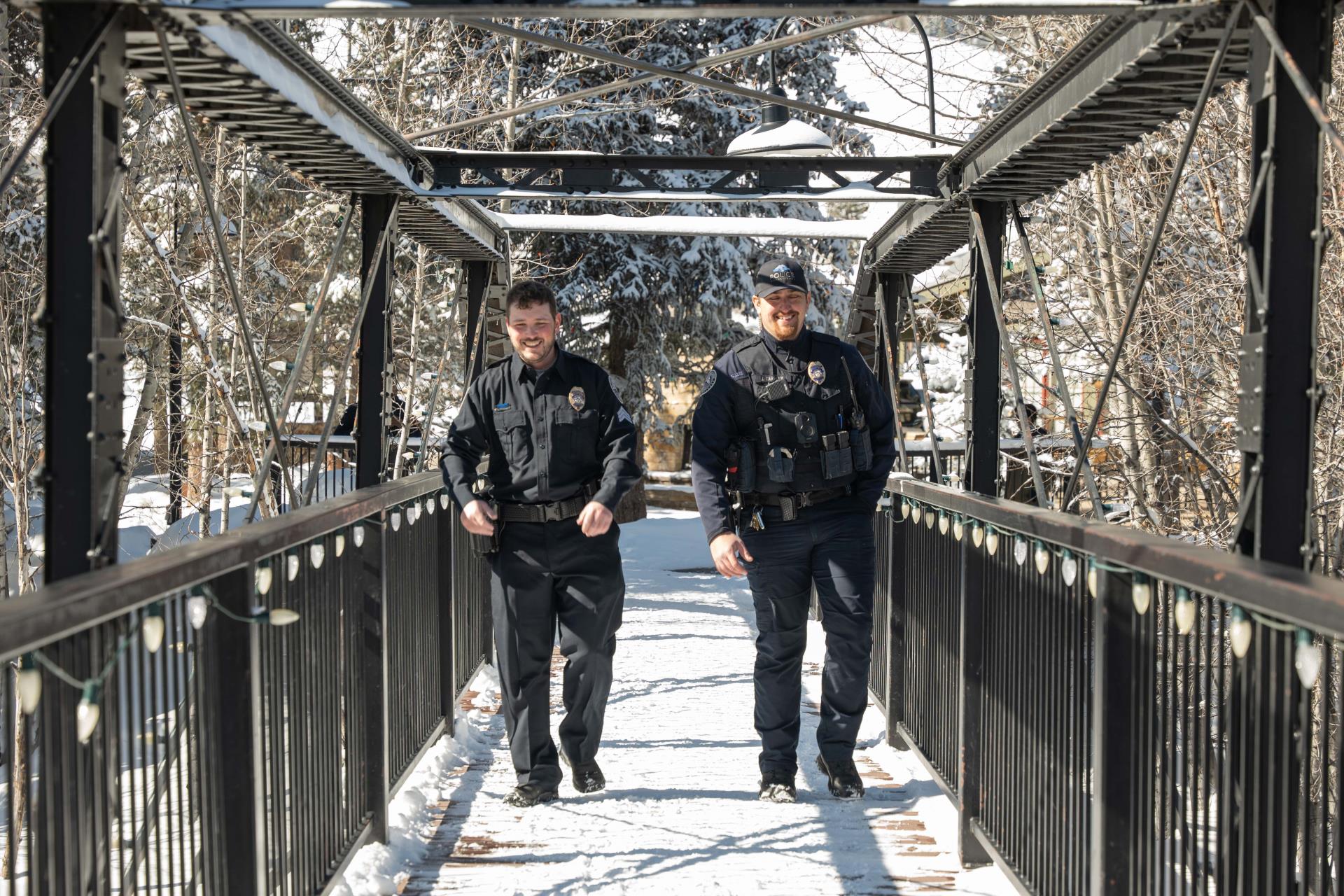 two male police officers walk across snowy bridge