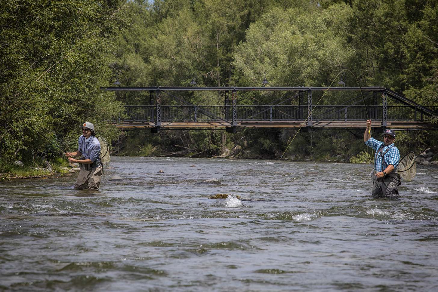 men fly fishing on blue river